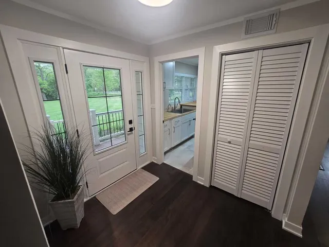 a view of a hallway with wooden floor and a bathroom