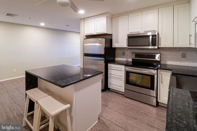 a kitchen with stainless steel appliances a stove a microwave a sink and white cabinets