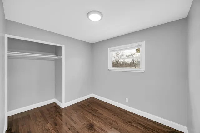 an empty room with wooden floor and window