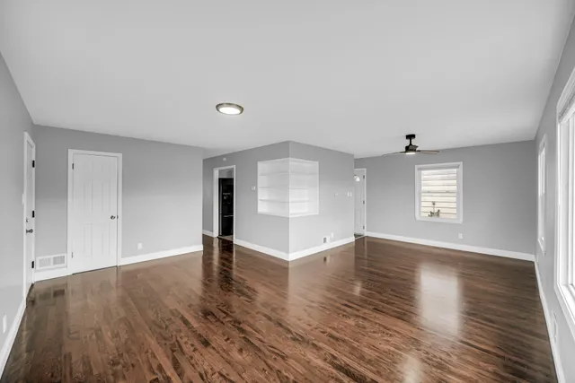 an empty room with wooden floor and windows