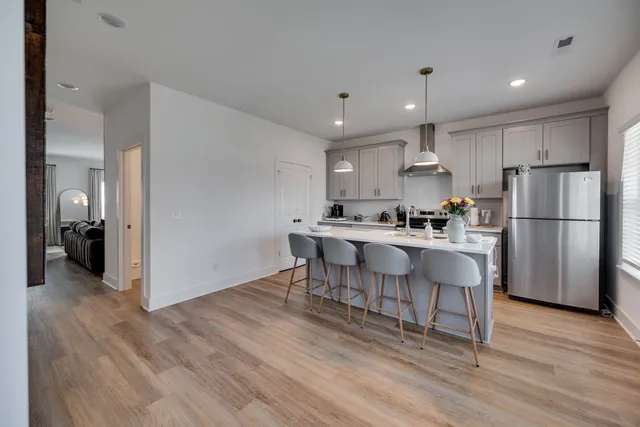 a kitchen with kitchen island granite countertop a refrigerator and a stove top oven