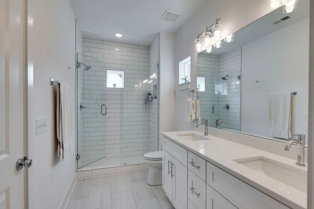 a bathroom with a granite countertop sink a toilet a mirror and shower
