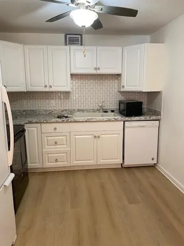 a kitchen with granite countertop a sink a stove and cabinets