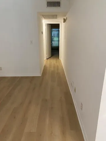 a view of a hallway with wooden floor and a white door