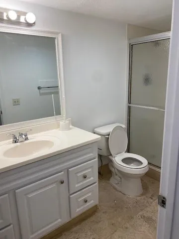 a bathroom with a granite countertop toilet sink and mirror