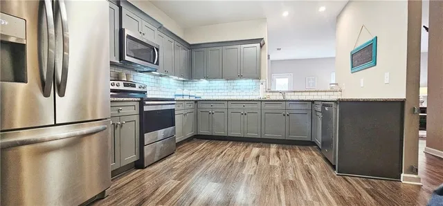 a kitchen with stainless steel appliances granite countertop hardwood floor sink stove and refrigerator
