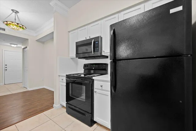 an empty room with wooden floor chandelier fan and windows