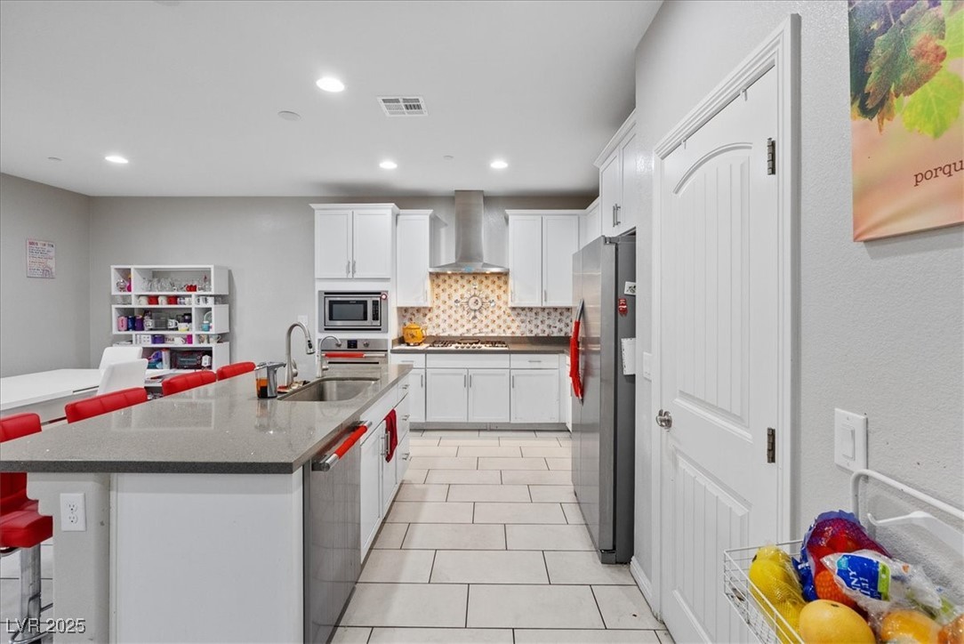 936 Keesey Way Henderson, NV 89052 - Photo 7 of 30 Kitchen with a kitchen bar, white cabinets, decorative backsplash, stainless steel appliances, and recessed lighting