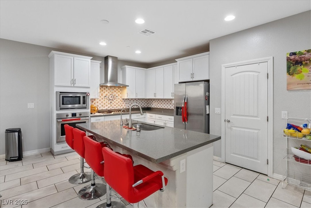 936 Keesey Way Henderson, NV 89052 - Photo 8 of 30 Kitchen featuring a kitchen breakfast bar, a center island with sink, stainless steel appliances, dark stone countertops, and backsplash