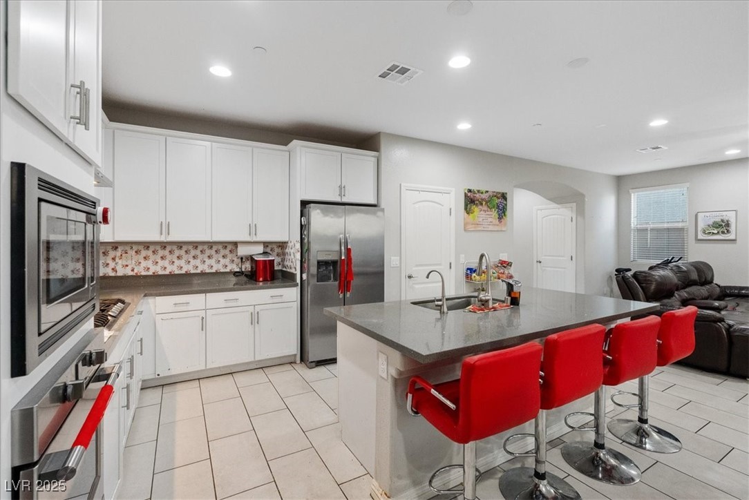 936 Keesey Way Henderson, NV 89052 - Photo 30 of 30 Kitchen featuring open floor plan, a breakfast bar, stainless steel appliances, tasteful backsplash, and a kitchen island with sink