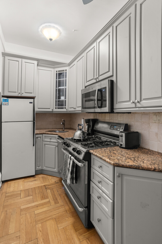 12 East 87th Street, Unit 6D Manhattan, NY 10028 - Photo 7 of 8 a kitchen with granite countertop cabinets stainless steel appliances and a sink