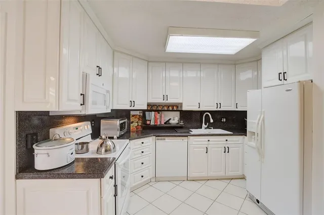 a kitchen with white cabinets sink and white appliances