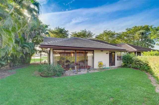 a backyard of a house with lawn chairs plants and tree