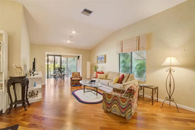 a living room with furniture a floor to ceiling window and wooden floor