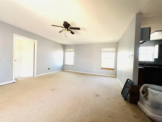 a view of empty room with windows and ceiling fan