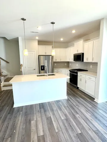 a large kitchen with kitchen island a sink dishwasher a stove and a refrigerator with wooden floor