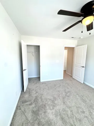 an empty room with windows and fan