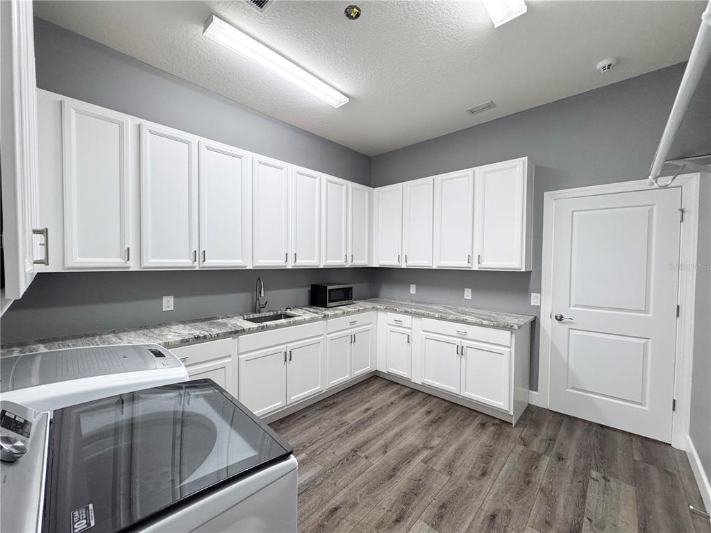 12822 Del Corso Loop Bradenton, FL 34211 - Photo 48 of 58 a kitchen with a sink dishwasher and white cabinets with wooden floor