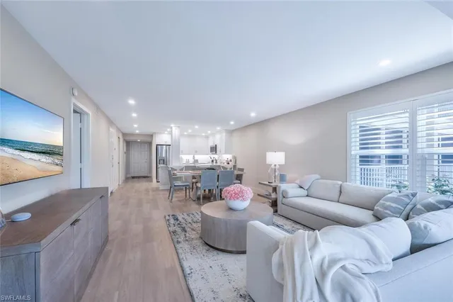 a living room with furniture a flat screen tv and a large window