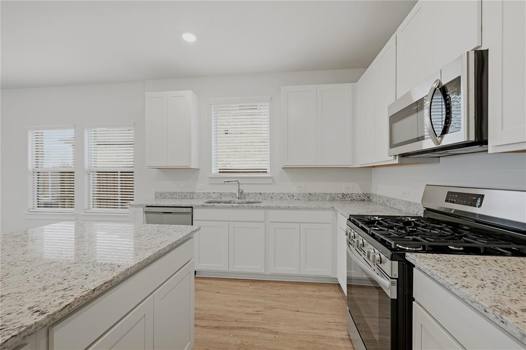 1346 Chisos Way Forney, TX 75126 - Photo 11 of 40 a kitchen with stainless steel appliances granite countertop a stove a sink and a microwave
