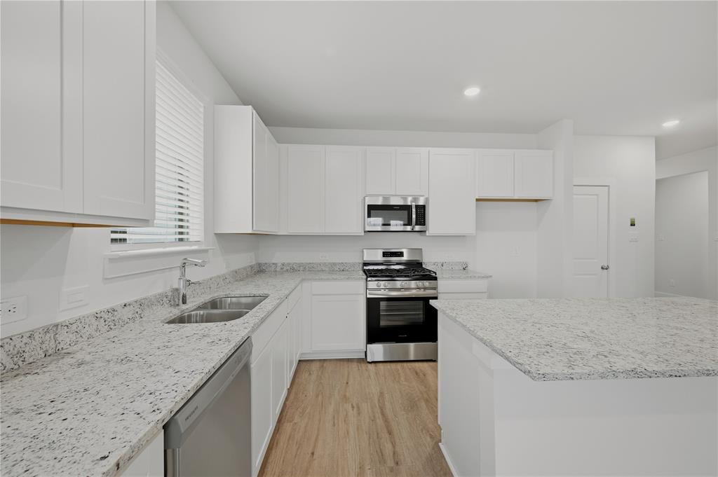 1346 Chisos Way Forney, TX 75126 - Photo 13 of 40 a kitchen with granite countertop a sink stove and cabinets