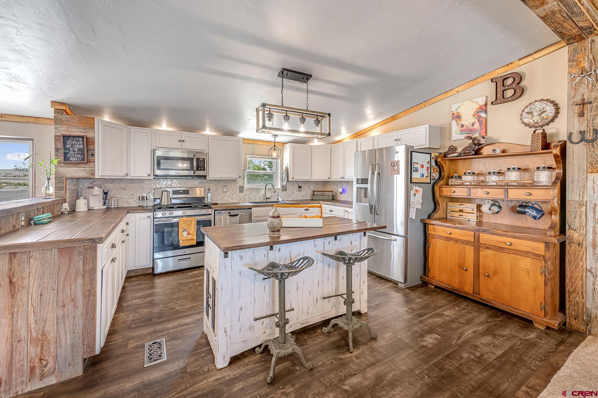 2787 2100th Road Delta, CO 81416 - Photo 15 of 40 a kitchen with stainless steel appliances a stove a sink dishwasher a refrigerator white cabinets and wooden floor