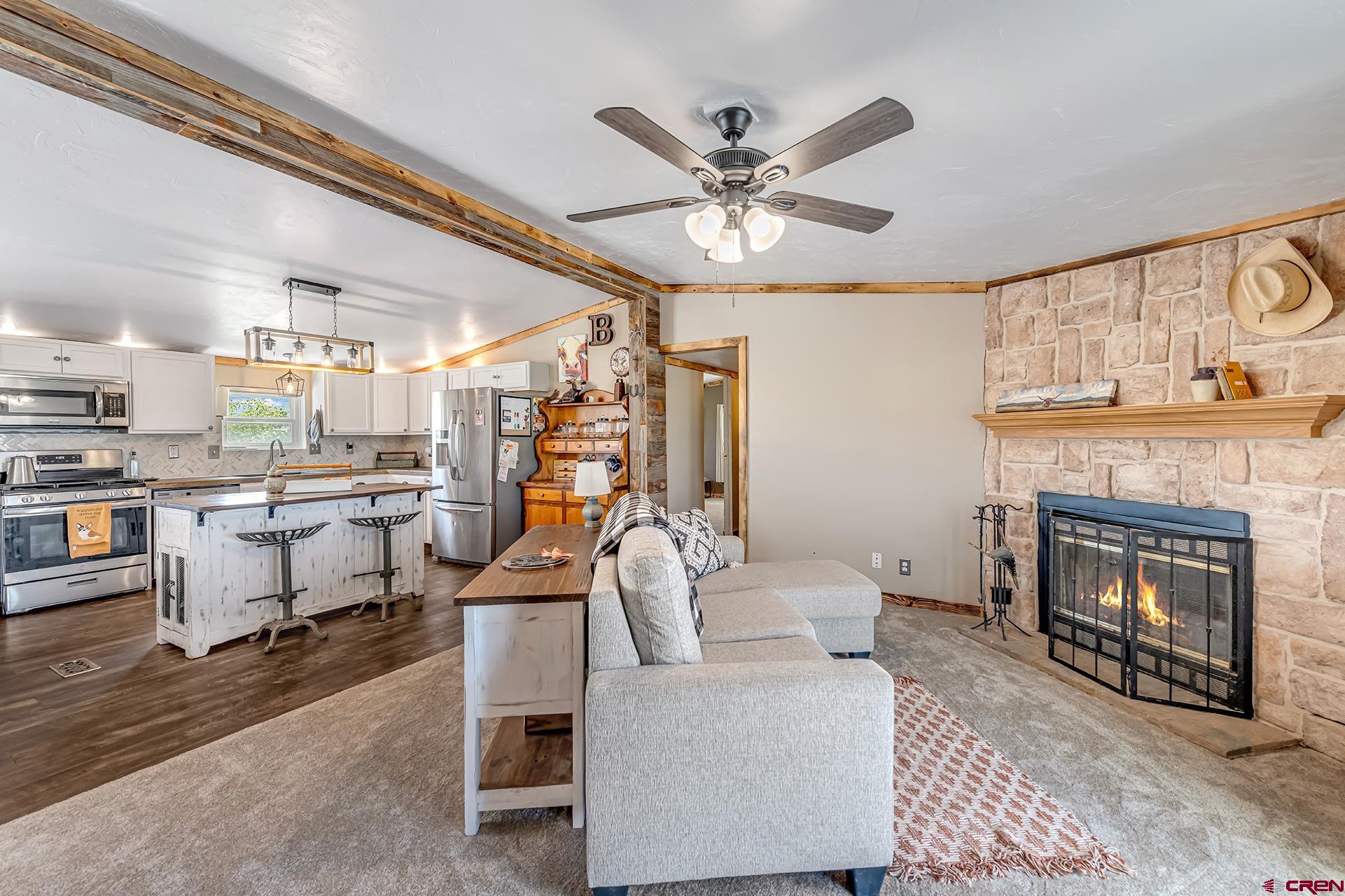 2787 2100th Road Delta, CO 81416 - Photo 17 of 40 a living room with furniture a fireplace and kitchen view