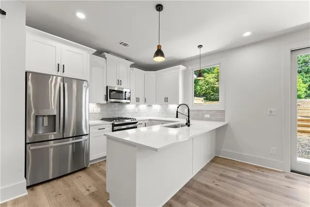 a kitchen with stainless steel appliances granite countertop a sink a stove a refrigerator and a window