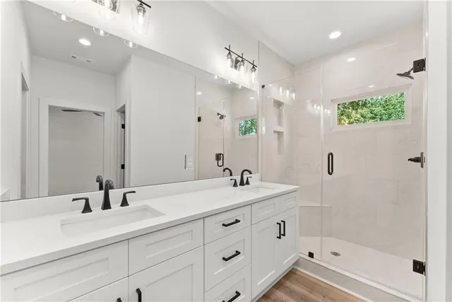 a bathroom with a sink double vanity granite tub shower and a mirror