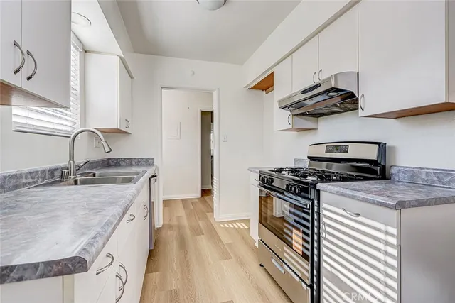 a kitchen with granite countertop a sink a stove and cabinets