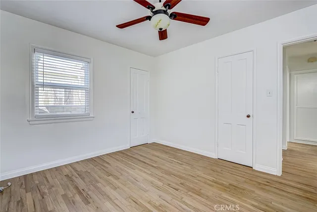 a view of empty room with wooden floor and fan