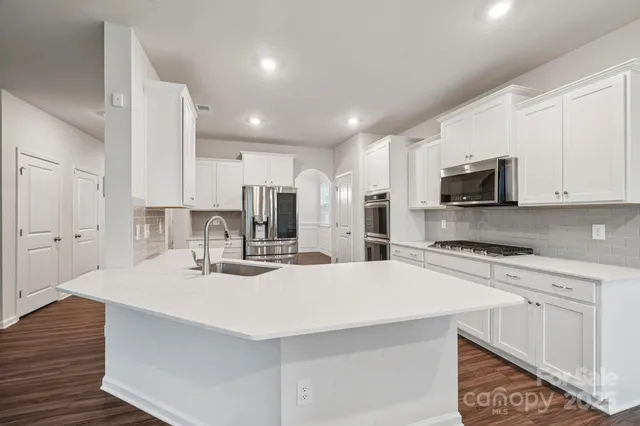 a kitchen with stainless steel appliances kitchen island granite countertop a wooden table and chairs