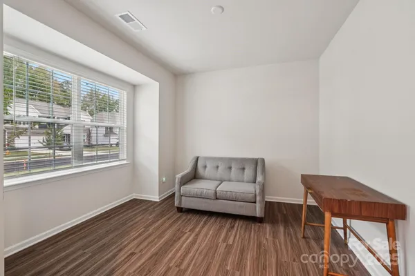 a large white kitchen with kitchen island a sink wooden floor and stainless steel appliances