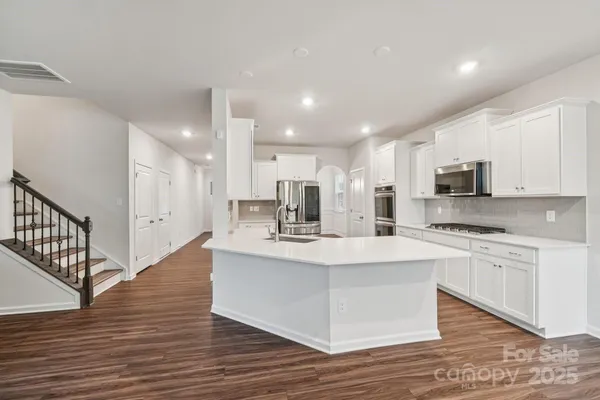 a kitchen with kitchen island a white counter top space cabinets and stainless steel appliances