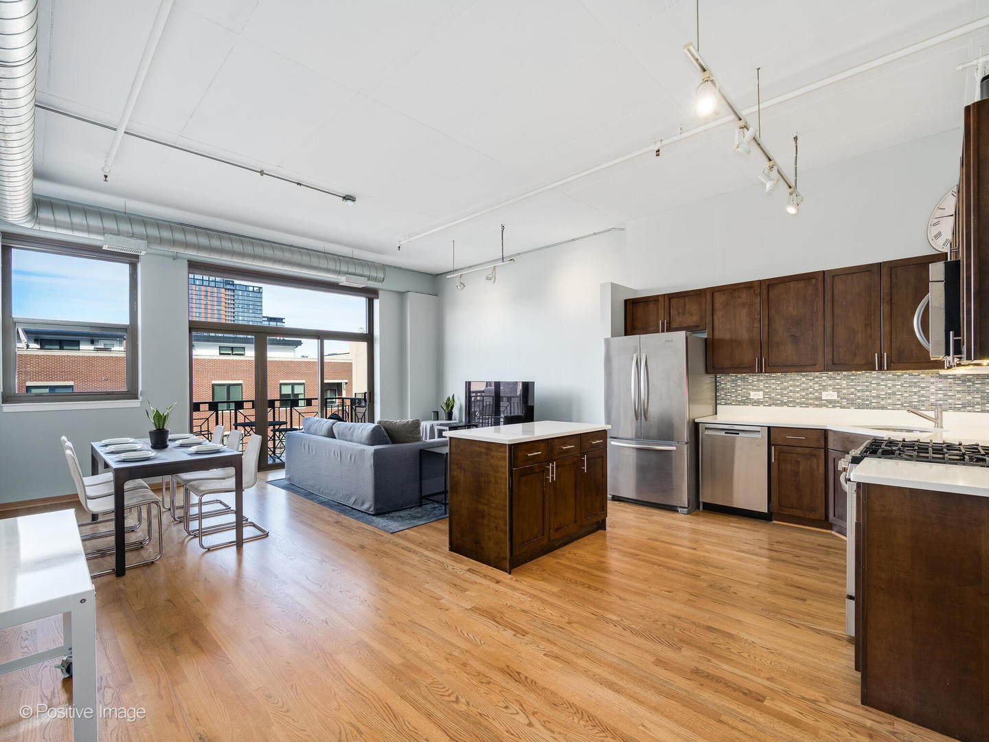 1301 West Madison Street, Unit 402 Chicago, IL 60607 - Photo 2 of 22 a kitchen with stainless steel appliances kitchen island granite countertop a stove top oven a sink a dining table and chairs with wooden floor