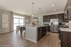 3622 Edelweiss Road Elgin, IL 60124 - Photo 4 of 11 a kitchen with stainless steel appliances granite countertop a refrigerator a sink dishwasher a stove and a dining table with wooden floor