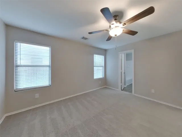 a view of an empty room with a ceiling fan and window