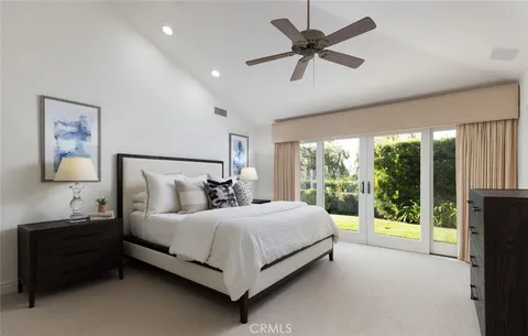 a bedroom with a bed painting and a large window