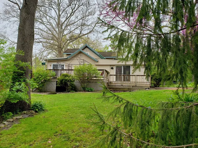 a view of a house with a big yard plants and large trees