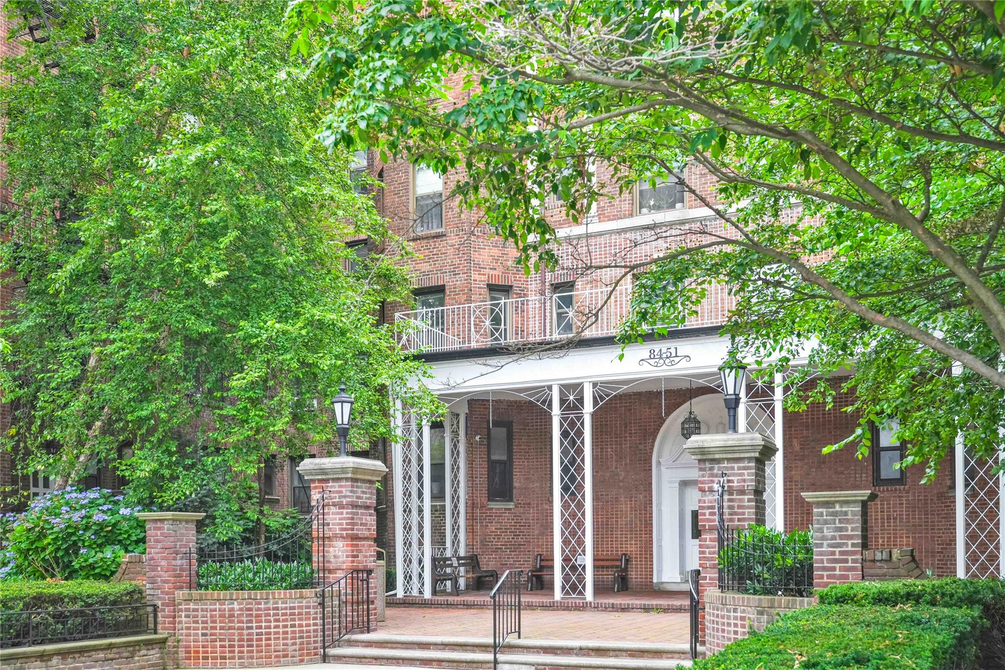 84-51 Beverly Road, Unit 5P Queens, NY 11415 - Photo 2 of 19 View of front facade with brick siding, covered porch, and a balcony