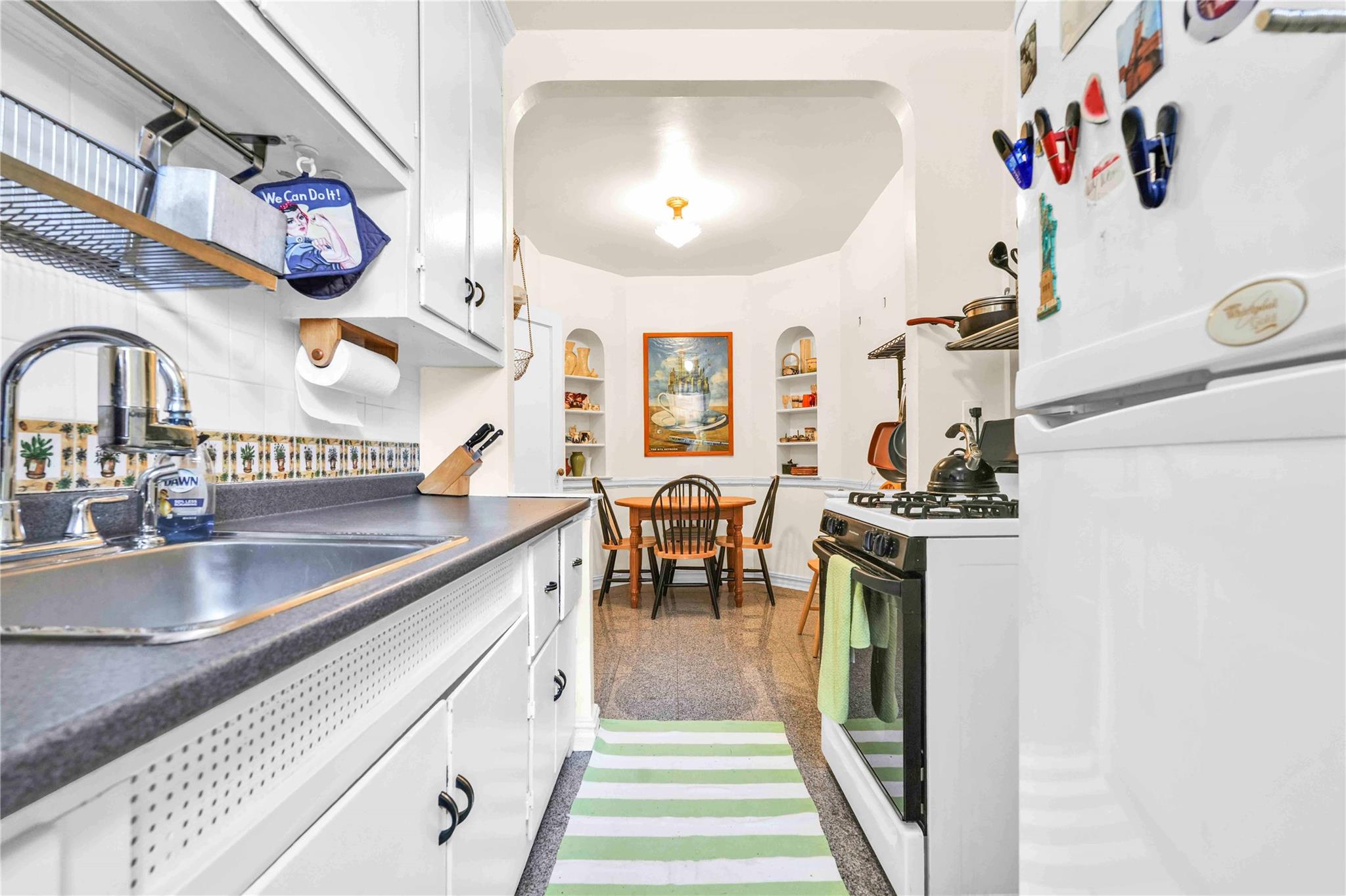 84-51 Beverly Road, Unit 5P Queens, NY 11415 - Photo 10 of 19 Kitchen featuring freestanding refrigerator, gas range oven, granite tiled floors, and white cabinets