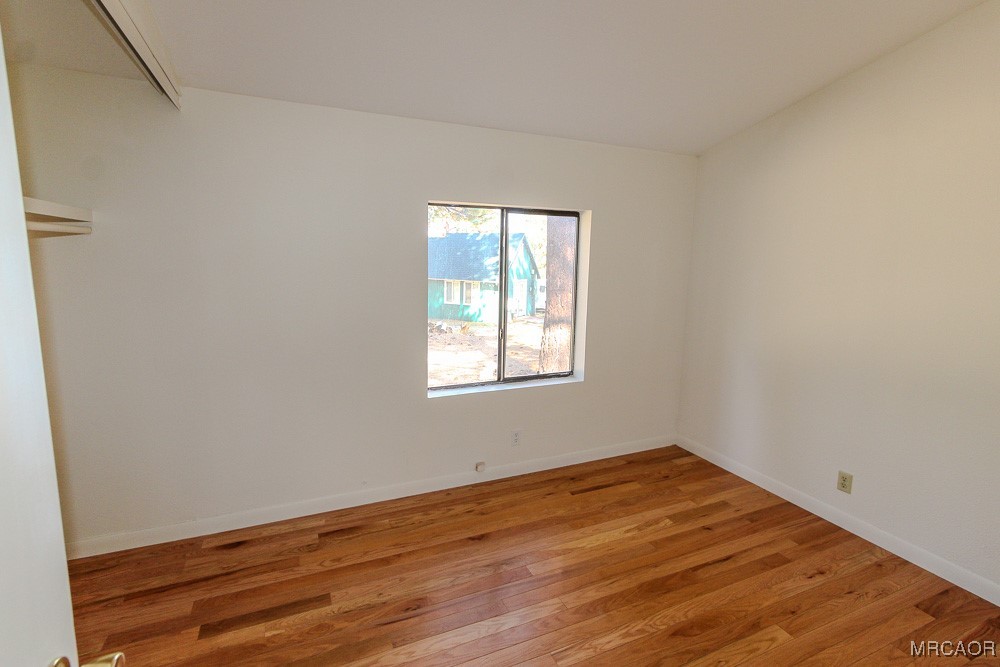 1197 Mitchell Lane Big Bear City, CA 92386 - Photo 13 of 32 an empty room with wooden floor and windows