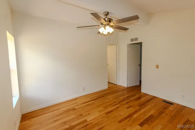 a view of a big room with wooden floor and a ceiling fan