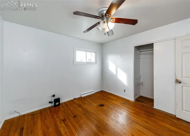 an empty room with wooden floor fan and windows