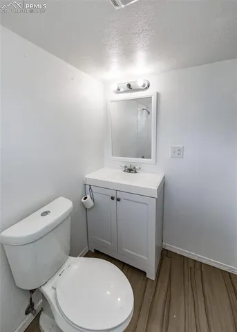 a bathroom with a toilet a sink and wooden floor