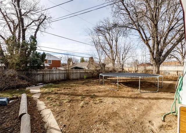 a view of a house with a large tree and wooden fence