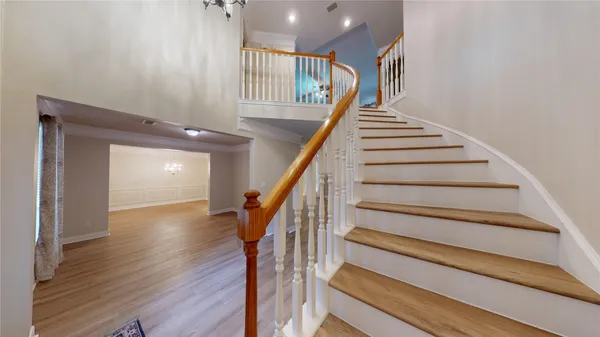 a view of a hallway with wooden floor and chandelier