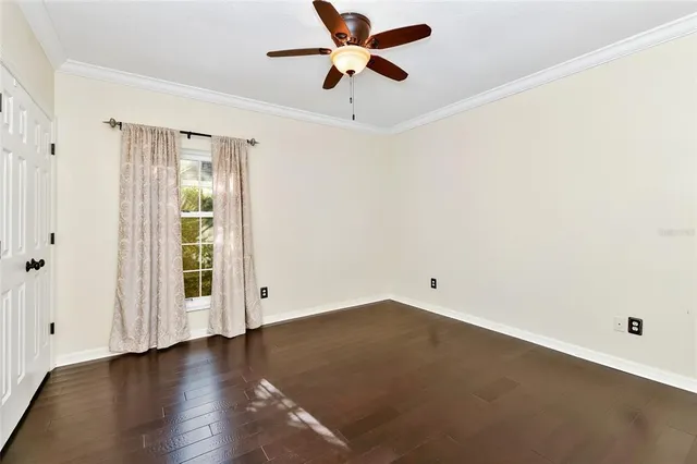 an empty room with wooden floor ceiling fan and windows