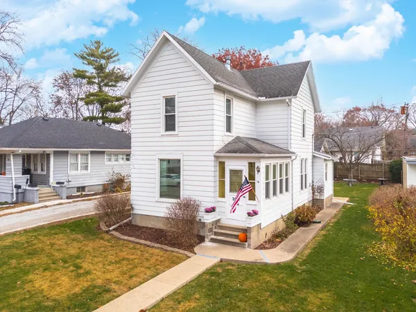 a front view of house with yard and trees in the background