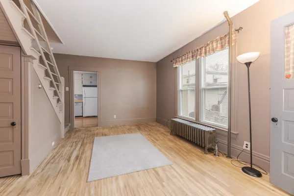 a view of an empty room with a window and wooden floor
